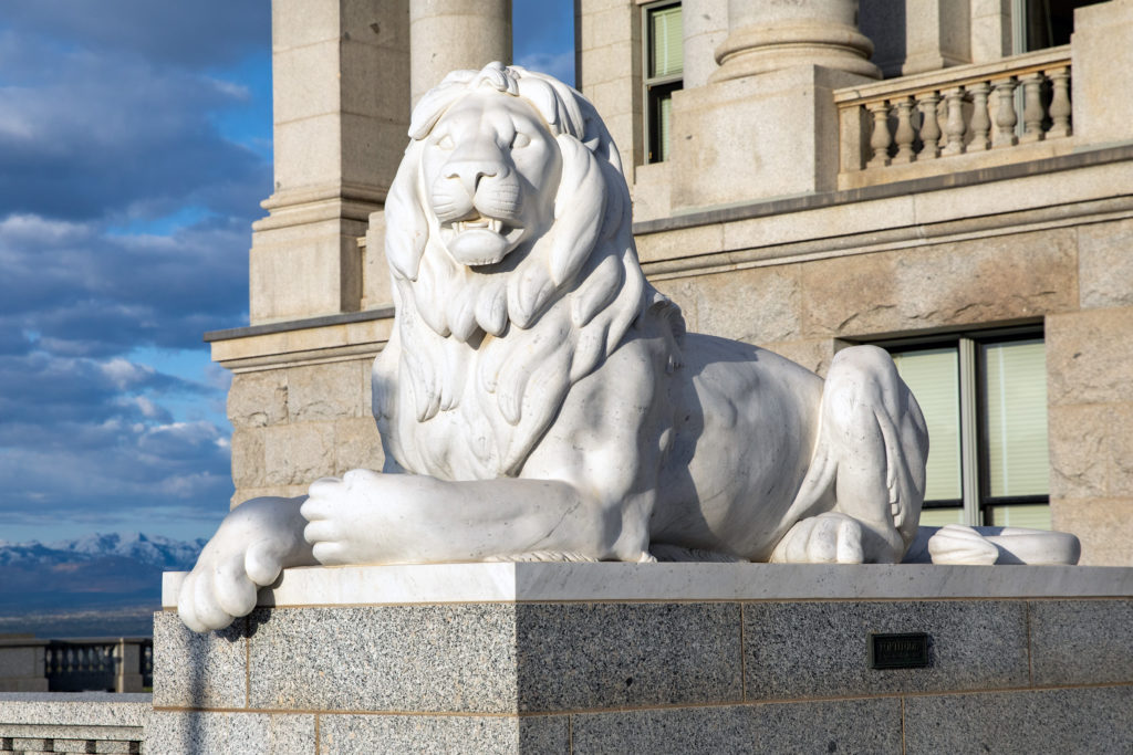 Marble sculpture of a lion laying down depicting fortitude at the entry way of the Utah State Capitol.