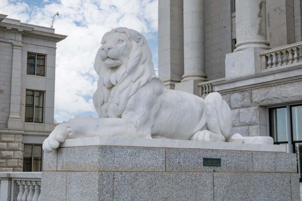 Marble sculpture of a lion laying down depicting honor at the entry way of the Utah State Capitol.