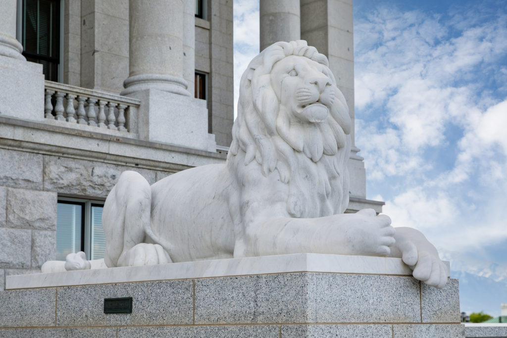 Marble sculpture of a lion laying down depicting patience at the entry way of the Utah State Capitol.
