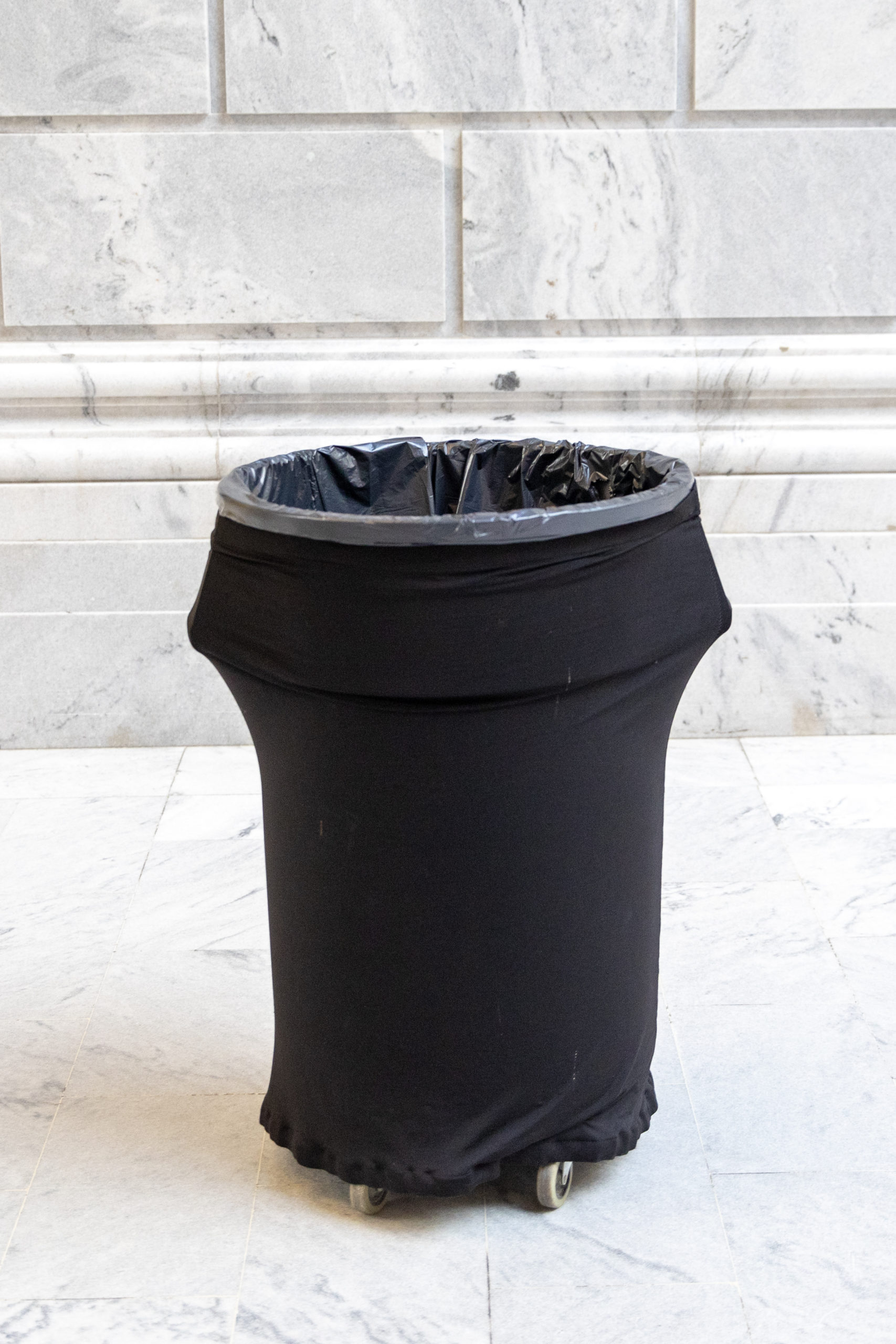 Black garbage can on marble backdrop