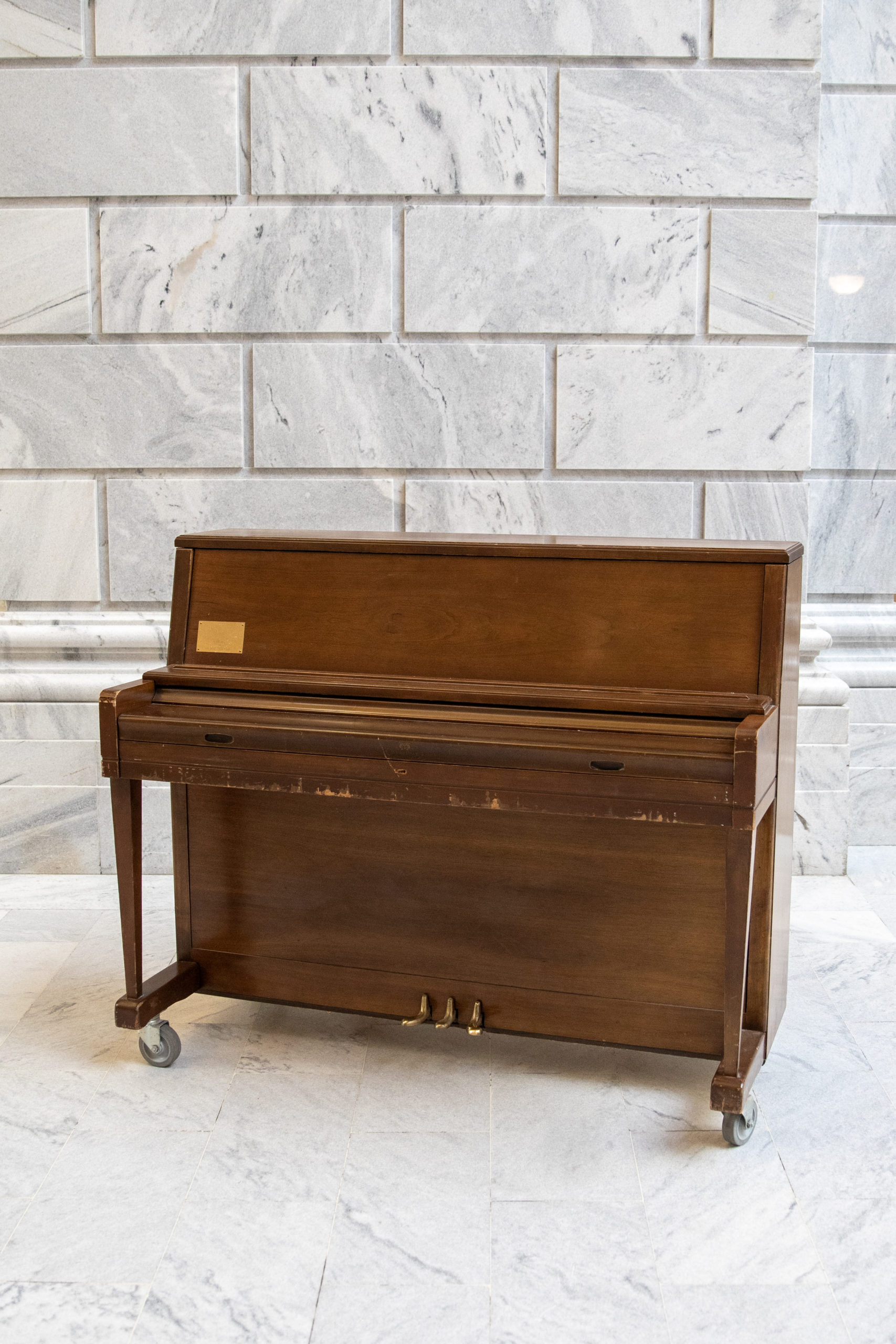 Upright wood piano on marble backdrop