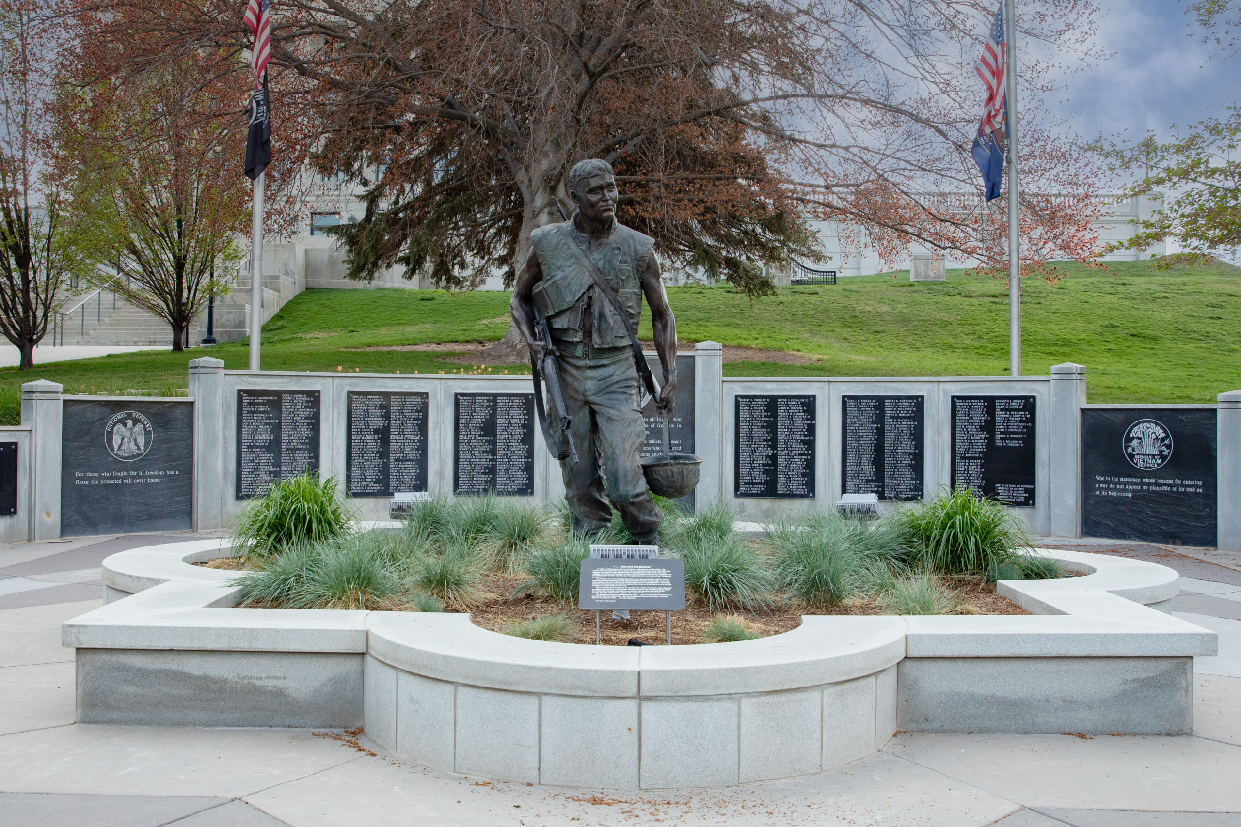 Bronze statue of Utah soldier outside at the Vietnam, Cambodia and Loas Veterans Memorial at the Utah State Capitol, with placards of names.